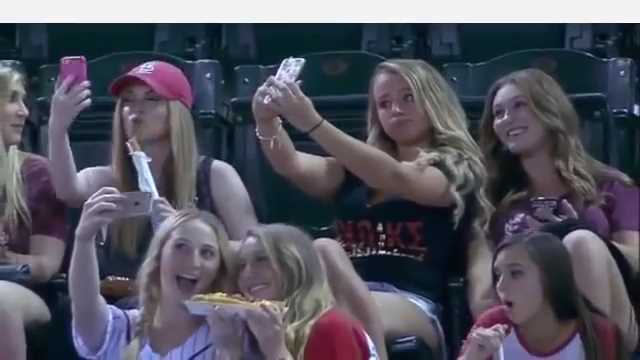 野球観戦そっちのけで自撮りに夢中な女子学生